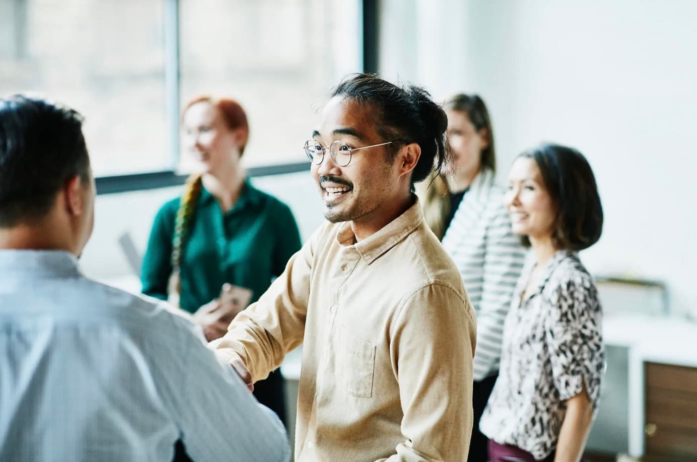 Inspire Management team members shaking hands and smiling in the office